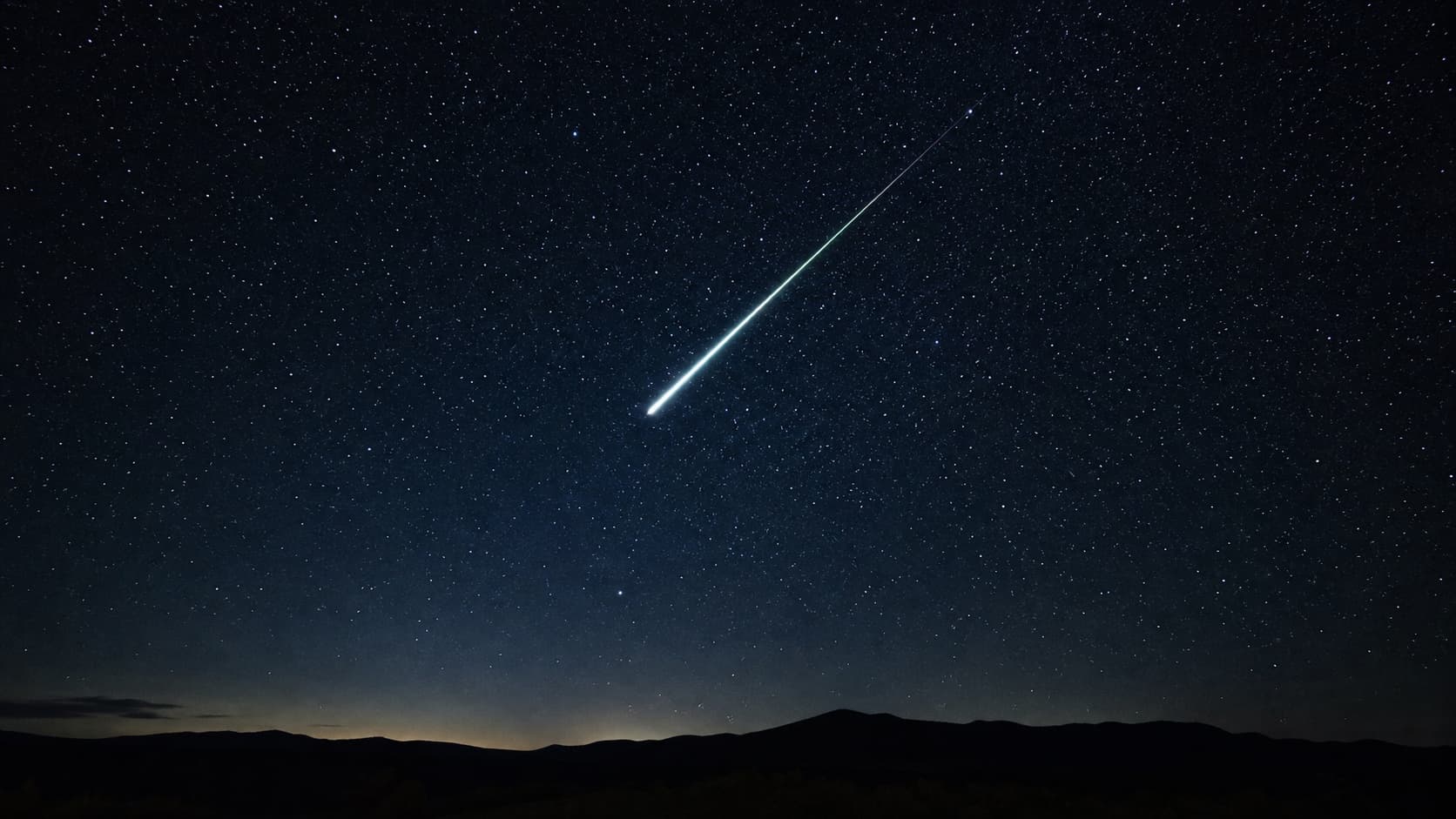 A bright meteor streaking across a starry night sky.