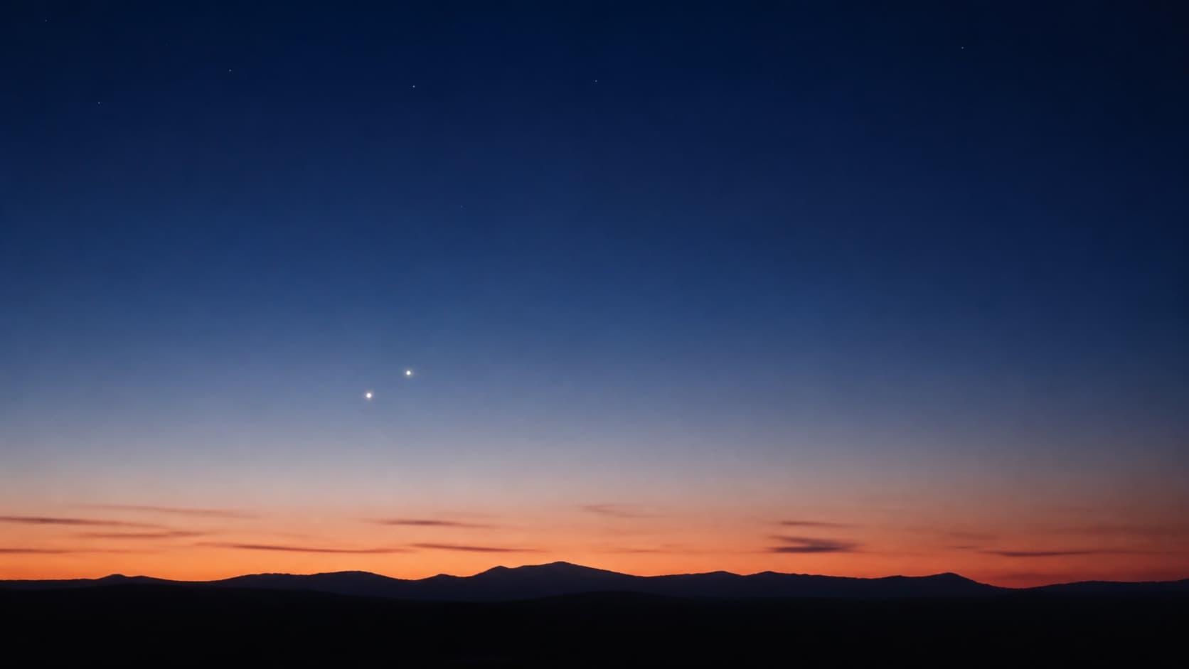 Two bright planets close together in a deep-blue twilight sky.