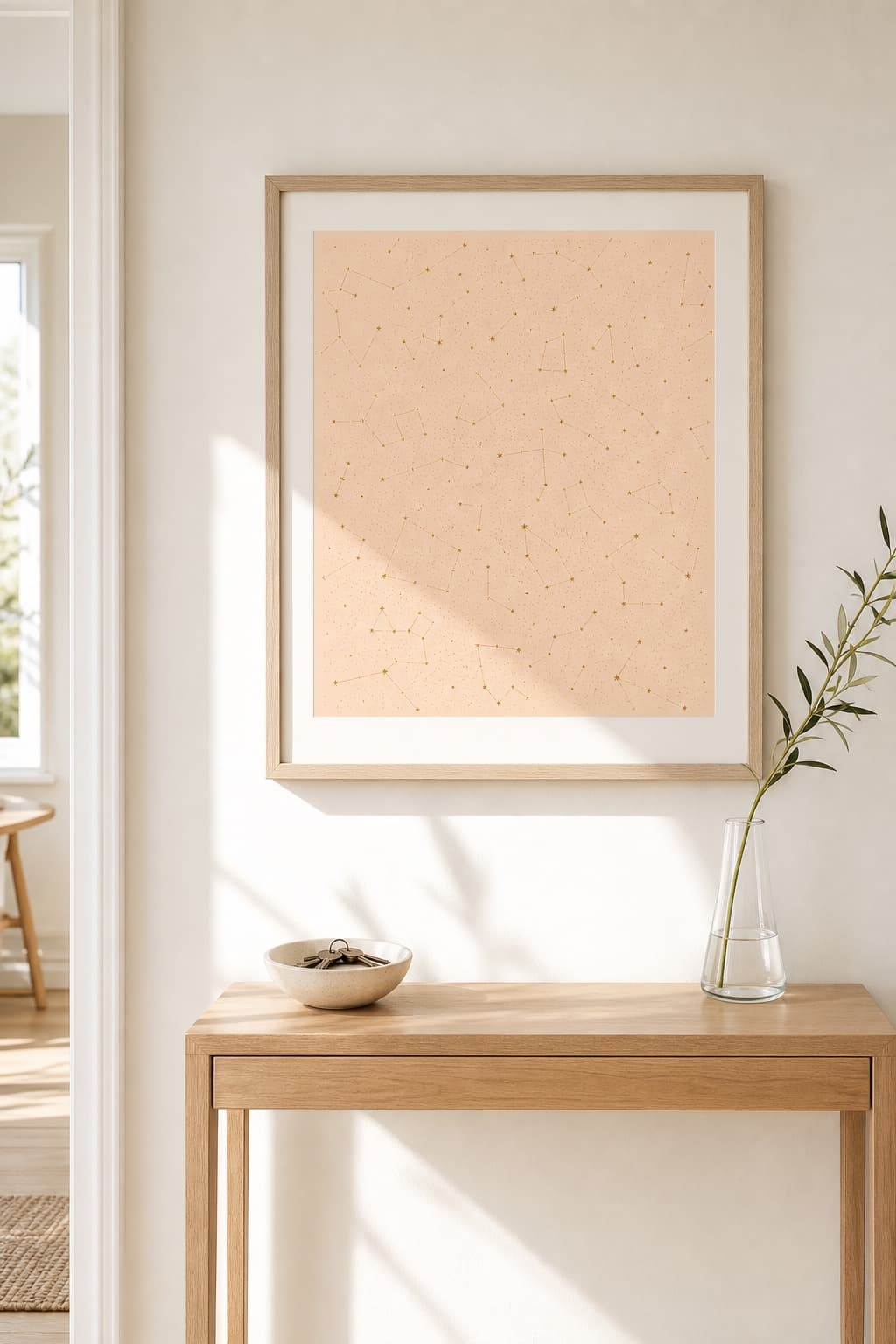 A peach-toned square star map poster in a clean entryway with a console table.